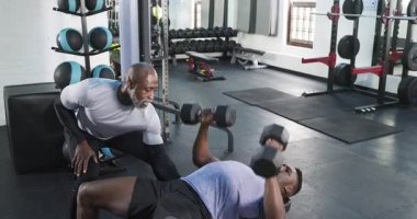 Antrenörde, antrenör güç ararken Afrikalı Amerikalı bir adam halterleri kaldırıyor. Güç, fitness, antrenman, spor, egzersiz, motivasyon, egzersiz