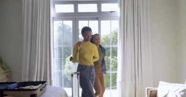 Çeşitli bayan arkadaşlar yatak odasına giriyor, bavullarını çekiyor ve hasır şapkalarını güneş gözlükleriyle şekillendiriyorlar. Yaşam tarzı, arkadaşlık, eğlence, seyahat, moda, aksesuarlar, günlük