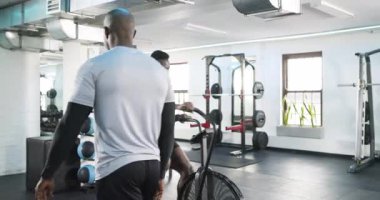 Afrika kökenli Amerikalı koç ve spor salonunda pedal çeviren stajyer koç giriş pozisyonunu ayarlıyorlar. Fitness, antrenman, güç, motivasyon, dayanıklılık, minimalist, atletik