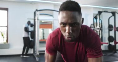 Afrika kökenli Amerikalı antrenman partnerleri spor salonundaki halterler ve plakalar için dambıl çekiyorlar. Zindelik, güç, eğitim, ortaklık, ekipman, motivasyon, sağlık