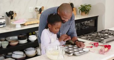 Afrika kökenli Amerikalı baba ve kız mutfak tezgahında yumurta pişirmek için kek kutusu yerleştiriyorlar. Aile, eğitim, işçilik, evcil, rahat, eğitici, aşçılık