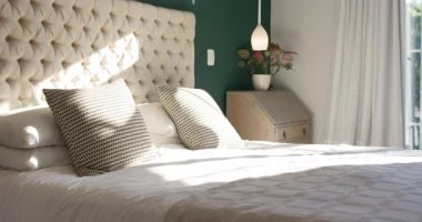 Pencereden süzülen güneş ışığı yatak örtüsü boyunca döşeme yamaları ve geçen zamanı gösteren yastıklar. Yatak, iç mekan, rahat, doğal ışık, rahatlama, dekor, minimalizm