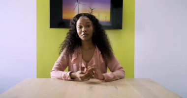 Afrika kökenli Amerikalı sunucu, ahşap masada rüzgar türbinleriyle el ele tutuşup el kol hareketi yapıyor. Profesyonel, iletişim, ilişki, minimalist, kurumsal, liderlik, konuşma