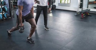 Afrika kökenli Amerikalı antrenör stajyer kettlebell 'e hareket çekerek spor salonunda güç topladı ve beşlik çaktı. Güç, koşullanma, fitness, eğitim, egzersiz, egzersiz, motivasyon