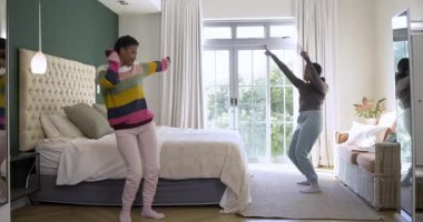 Farklı kadın arkadaşlar ekran dışında müzik eşliğinde dans ediyor yatağa atlıyor yatak odasında sırtüstü gülüyor. Neşeli, toplum, rahatlama, gündelik, canlı, uyum, dostluk