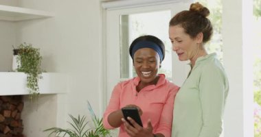 Uygulama demosunu takip eden çeşitli bayan arkadaşlar akıllı telefon çalarken ve evde gülümserken. Arkadaşlık, teknoloji, bağlantı, eğlence, modern, iletişim, akıllı telefon.