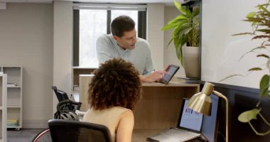 Çizelge çıkardıktan sonra, çalışma masasında çalışan çeşitli iş arkadaşları dizüstü bilgisayara ve tablete işaret ediyor. İşbirliği, takım çalışması, üretkenlik, modern, ofis, teknoloji, iletişim