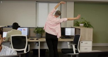 Ofise olgun bir kadın giriyor ve Hintli iş arkadaşına monitörlerden rehberlik ediyor. İşbirliği, verimlilik, modernleşme alanı, takım çalışması, sağlık, odaklanma, kurumsal