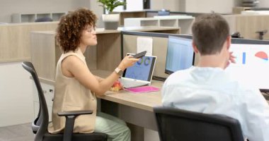 Masada oturan bir kadın dizüstü bilgisayarın çizelgelerine bakıyor akıllı telefona bakıyor ve meyve salatası tadıyor, fotokopi çekiyor. İşbirliği, verimlilik, beslenme, odaklanma, modern, işyeri, refah