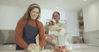 Parlak mutfakta köpekleri kemirdikten sonra hamuru yoğururken gülen çift. Samimi, evcil, neşeli, samimi, yaşam tarzı, samimi, enerjik.