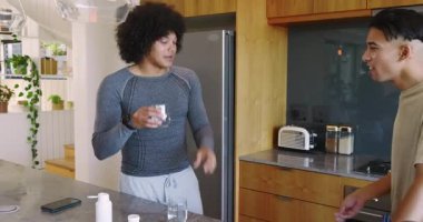 Muhtelif arkadaşlar, takviye kabından alınan tozu ölçüyor ve mutfak adasında suyu yudumluyorlar. İşbirliği, sağlık, sağlık, gündelik, modern, yaşam tarzı, arkadaşlık