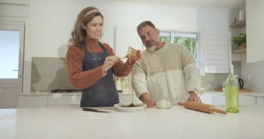 Şarap doldurduktan sonra, hamuru şekillendiren bir çift mutfak adasında tatlı olarak çikolatayı kaseye karıştırdılar. Çift, pişirme, modern, konforlu, aşçı, samimi, hazırlık