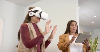 Beyaz VR kulaklık takan, demoyu yöneten, ofiste tablet kullanan çeşitli bayan meslektaşlar. Futuristik, işbirliği, teknoloji, yenilik, dijital, profesyonel, arayüz