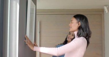 Kadın arkadaşlarını asmak, evdeki beyaz çerçeveli resmi sarı bant kullanarak eve asmak. İşbirliği, ev dekorasyonu, modern iç mekan, çalışma alanı, arkadaşlık, hassasiyet, minimalizm