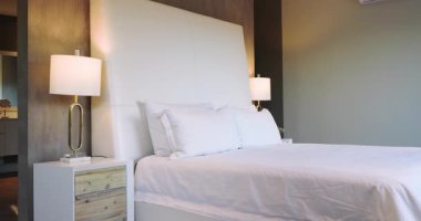 Kayıt başladığında, kamera beyaz yatağın üzerinde dönüp komodinleri ve lambaları gösteriyor. Lüks, minimalizm, iç mekan, rahat, zarif, çağdaş, gevşeme