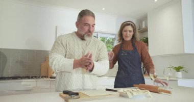 Özel bir çift, yemek pişirmek için tezgahın üstünde pizza keskisiyle kafes kabuğu örüyor. Romantizm, işbirliği, aşçılık, modern, ev, sıcaklık, zarafet