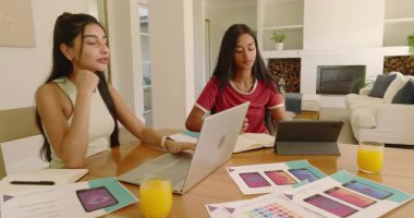 Dizüstü bilgisayarı açtıktan sonra, çeşitli kadınlar yemek masasında renk paletlerini tasarım planlaması için değiş tokuş ettiler. İşbirliği, takım çalışması, yaratıcılık, tasarım, dijital, çalışma alanı, yaşam tarzı