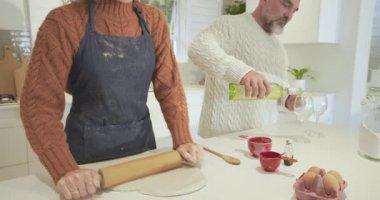 Mutfak adasında tost için bardakları doldurmadan önce yuvarlanan hamurlar ve şarap şişeleri. Aile içi, aşçılık, kırsal, yaşam tarzı, konfor, kutlama, uyum.