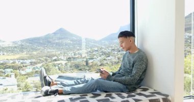 Akıllı telefonu kontrol eden erkek arkadaşlar, pencere kenarındaki bankta kucaklaşıp vadi manzarasını, fotokopi alanını paylaşıyorlar. Gündelik, dostluk, arkadaşlık, kentsel, manzaralı, sakin, modern