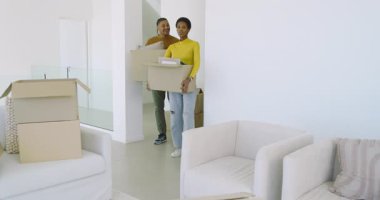 Çeşitli çiftler eve taşınıyor, kutuları açıyor, oturma odasında yastık ve çerçeve düzenliyorlar. Ev, taşınma, iç mekan, yaşam tarzı, modern, ikamet, karşılama