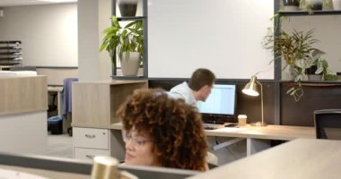 Çalışma masasındaki çeşitli iş arkadaşları çift ekran raporlarını tartışırken yönetici esniyor ve yürüyor. İşbirliği, iletişim, takım çalışması, modern, profesyonel, üretkenlik, çalışma alanı