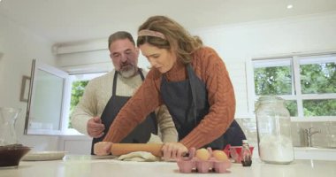 Bir çift hamuru yuvarlıyor, kadın iğne topluyor ve erkek mangırı düzleştiriyor. Aile içi, aşçılık, işbirliği, konforlu, yaşam tarzı, kırsal, neşeli