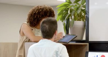 Çeşitli iş arkadaşları ofise tabletle giriyor. Masanın bölümlerine yaslanıyor ve veri noktalarına dokunuyor. İşbirliği, takım çalışması, analitik, dijital, üretkenlik, modern, iletişim