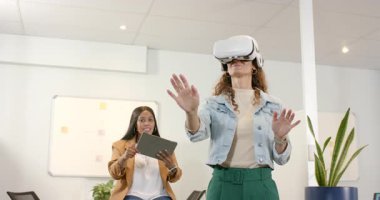 Çeşitli iş arkadaşları tableti tıkırdatıyor ve modern ofiste VR kulaklıkla işaret ediyor, arayüzü test ediyorlar. Fütüristik, işbirliği, teknoloji, yenilik, şirket, katılım, dalkavukluk