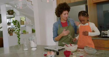 Anne ve kızı elek ile dans etmeden önce adada kek tenekesi yerleştiriyor hamuru karıştırıyor. Aile, işbirliği, neşeli, köylü, neşeli, yerli, eğlenceli