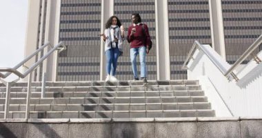 Bina girişinden iniyor, farklı arkadaşlar telefonları kontrol ediyor ve merdivenlerden kahveyle iniyor. Kentsel, dostluk, işbirliği, gündelik, modern, yaşam tarzı, iletişim