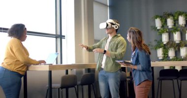 VR kulaklık takan adam dinlenme odasındaki VR testi sırasında dizüstü bilgisayarın kontrollerini araştırıyor. İşbirliği, teknoloji, yenilik, takım çalışması, dijital, çalışma alanı, geleceksel