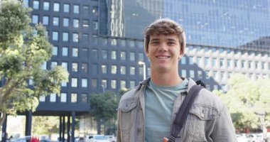 Kamera solda, garajı gösteriyor. Adam çanta tutuyor ve ofis binasından önce gülümsüyor. Kentsel, profesyonel, güncel, çağdaş, mimari, yaşam tarzı, kentsel giyim