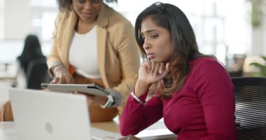 Dizüstü bilgisayarı işaret eden, veri girişine rehberlik eden ve ofis masasındaki tableti tıklatan çeşitli kadın iş arkadaşları. İşbirliği, takım çalışması, çalışma alanı, profesyonel, danışmanlık, iletişim, üretkenlik