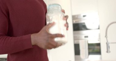 Hamur hazırlayan, Afrika kökenli Amerikalı adam kavanozu sallıyor, kepçeyle un topluyor, mutfakta kâseye un karıştırıyor. Fırın, aşçılık, fırın, yerli, tarif, mutfak gereçleri, hazırlık.