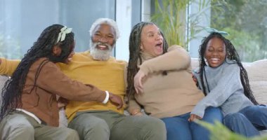 Torunları sürpriz bir giriş yaptıktan sonra farklı aileler oturma odasında gri kanepede sarılıyor. Aile, jenerasyon, bağlantı, sıcaklık, şefkat, boş zaman, sade