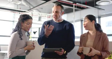 Tableti inceleyen olgun bir adam çeşitli iş arkadaşlarına ofis bölmeleriyle el kol hareketi yapıyor. İşbirliği, takım çalışması, iletişim, modern, profesyonel, tartışmalı, cilalı