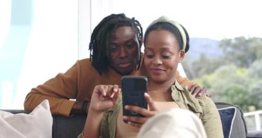 Afrika kökenli Amerikalı bir çift kollarını omzunun üstünden geçirip akıllı telefonun kilidini açıyor ve kanepede yemek yiyorlar. Çift, arkadaşlık, yakınlık, rahatlama, modern, samimi, boş zaman