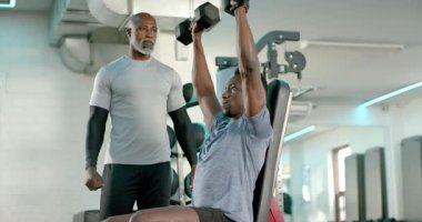 Kıdemli Afrika kökenli Amerikalı antrenör, kollarını kaldırıyor. Spor salonunda halterler üzerinde güç toplayan müşteriye rehberlik ediyor. Zindelik, güç, egzersiz, eğitim, performans, motivasyon, sağlık