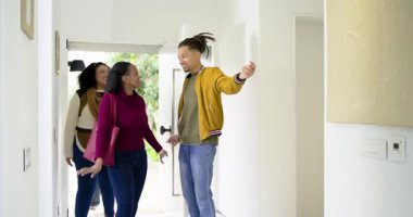 Hardal ceketli orta yaşlı bir adam ön kapıyı açıyor, modern yaşam alanına dostları davet ediyor. Çağdaş, misafirperver, sosyal, iç mimari, üst sınıf, zarif, neşeli