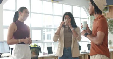 Muhtelif bayan meslektaşlar, ofisteki kupadan yudumlayarak, sağ meslektaşlarının jestleriyle konuşmaya başlıyorlar. İşbirliği, takım çalışması, iletişim, modern, profesyonel, çalışma alanı, gayri resmi
