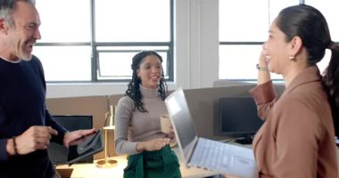 Çeşitli iş arkadaşları laptop verilerini fark ediyor, el sallıyor, beşlik çakıyor, modern ofiste başarıyı kutluyorlar. İşbirliği, takım çalışması, yenilik, modernlik, üretkenlik, gündelik, profesyonel