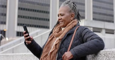 Kıdemli Afro-Amerikalı kadın telefonu kaydırıyor, gülümsüyor ve plaza pervazında gülüyor, kopyalama alanı. Kentsel, teknoloji, yaşam tarzı, gündelik, neşeli, olgun, bağlantı