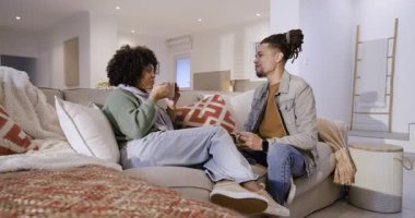 30 'lu yaşlarda erkek ve 20' li yaşlarda kadın arkadaşlar ellerinde fincanlarla evdeki kanepede sohbet ediyorlar. Gündelik, dostluk, konukseverlik, iç mekan, modern, sohbet, sıcaklık