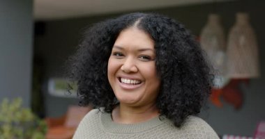 Yetişkin bir kadın süveter giyip kameralar önünde gülerken verandada elinde hasır ışıklarla gülüyor. Portre, mutluluk, rahatlama, açık hava, günlük kıyafet, neşe, yaşam tarzı