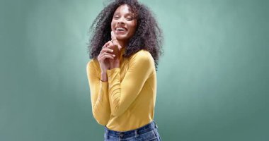 Sarı kazaklı, kollarını çaprazlayan, yeşil arka planda duran kendinden emin bir kadın. Özgüven, portre, yetki, kadın, gündelik, moda