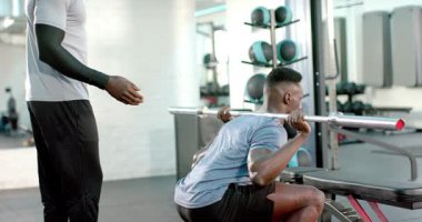 Kıdemli Afrika kökenli Amerikalı antrenör müşterisini spor salonunda halterle otururken görüyor ve güvenliği sağlıyor. Zindelik, güç, antrenman, spor, spor, profesyonel, disiplin