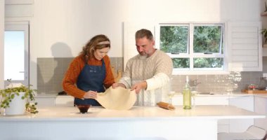 Mutfakta hamur kenarlarını kavrayan, tavanın içine kaldıran ve örten, turta kabuğu hazırlayan bir çift. Mutfak, takım çalışması, kırsal, parlak, yerli, gastronomi, uyum