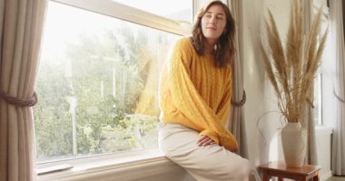 Yetişkin bir kadın evde gün ışığının düzeldiğini görüyor mercek parlayınca bahçeye doğru dönüyor. Sakin, sakin, rahat, minimalist, sıcak, yansıtıcı, doğal