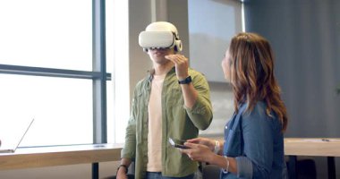 Asyalı adam eğitim için hocadan VR kulaklığı alıyor, eğitim odasında arayüzü keşfediyor. Sanal gerçeklik, dolambaçlı, teknoloji, eğitim, yenilik, dijital, etkileşim