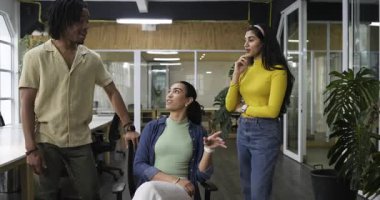 Çeşitli iş arkadaşları birbirini işaret ederek konuşur, el kol hareketleri yapar ve masalarda kahkahalarla son bulurlar. İşbirliği, takım çalışması, şirket, iletişim, modernlik, üretkenlik, ofis kültürü